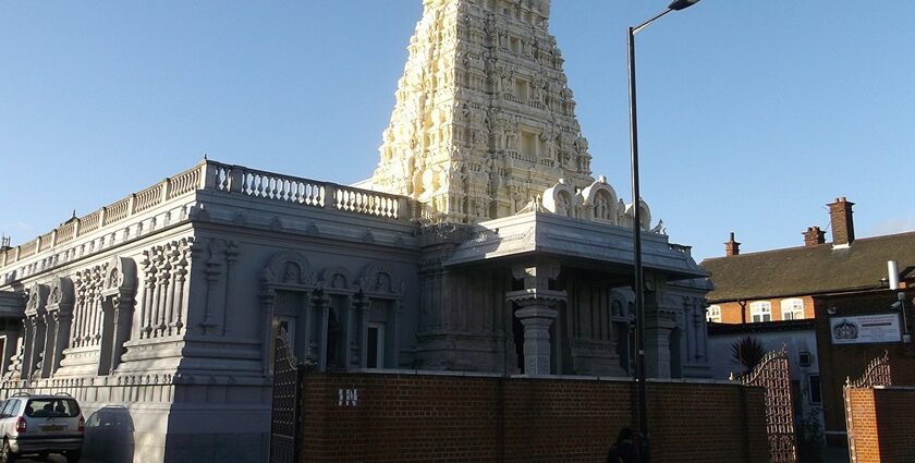 Murugan temple entrance with well-detailed pillars and motorcycles and cars parked.