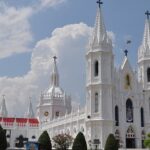 Front view of the Velankanni Temple with a tall Gothic architectural building and its area.