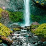 An image of a waterfall cascading over rocks surrounded by greenery.