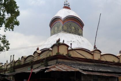 An image of Kalighat Temple entrance, surrounded by devotees and vibrant street vendors.