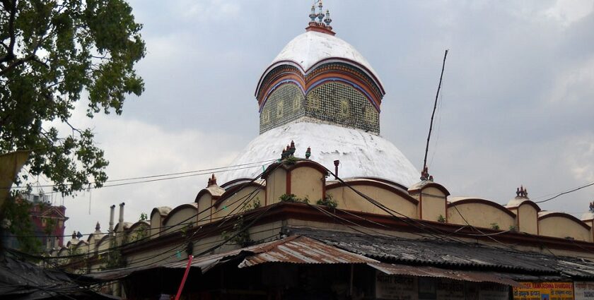 An image of Kalighat Temple entrance, surrounded by devotees and vibrant street vendors.