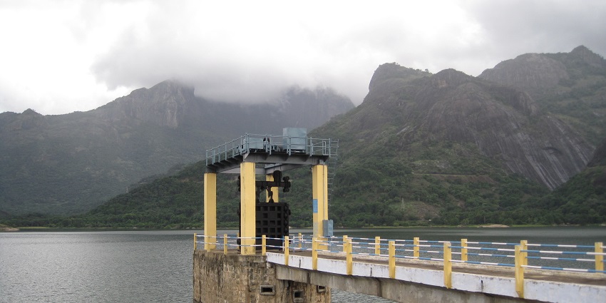 A serene view of Aliyar Dam surrounded by hills, one of the best places to visit in Valparai.