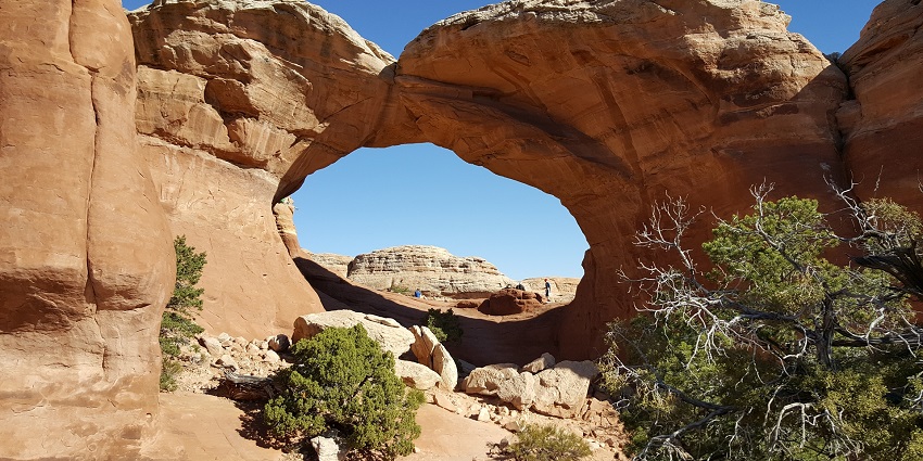 A view of Turret Arch in Arches National Park, with hikers exploring the landscape