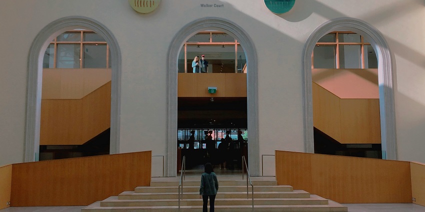 An art gallery that has a sculpture in its middle and is filled with paintings on the wall