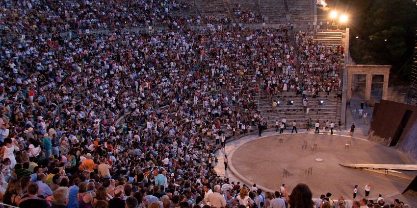 Athens Epidaurus festival with artists performing in the theatre and people watching.