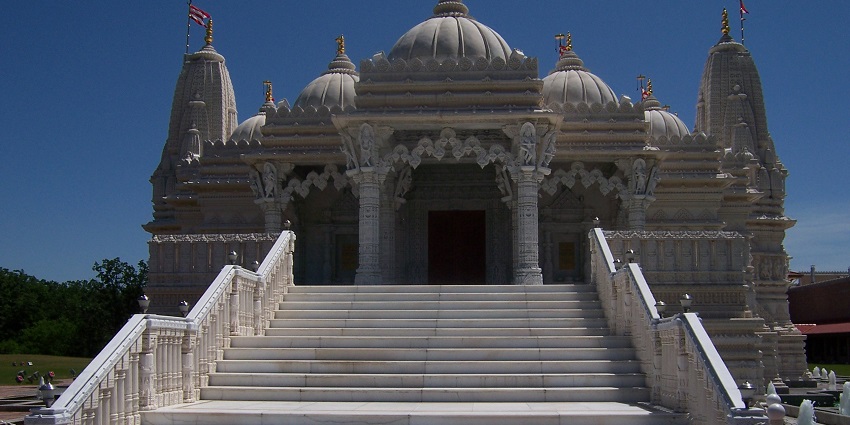 Aerial view of BAPS Shri Swaminarayan Mandir in Chicago with surrounding trees and roads.