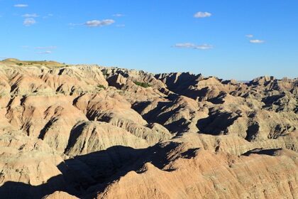 An image of the Badlands National Park covered by the blue sky and white clouds.