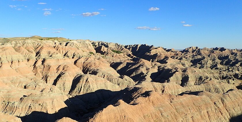 An image of the Badlands National Park covered by the blue sky and white clouds.