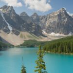 A view of Moraine Lake in Banff National Park, surrounded by snow-capped mountains and trees.