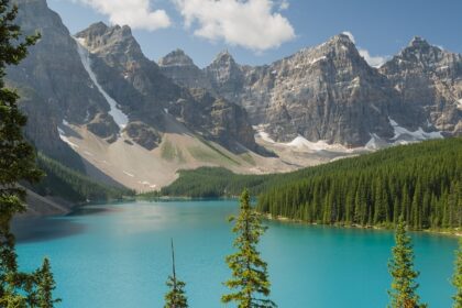 A view of Moraine Lake in Banff National Park, surrounded by snow-capped mountains and trees.