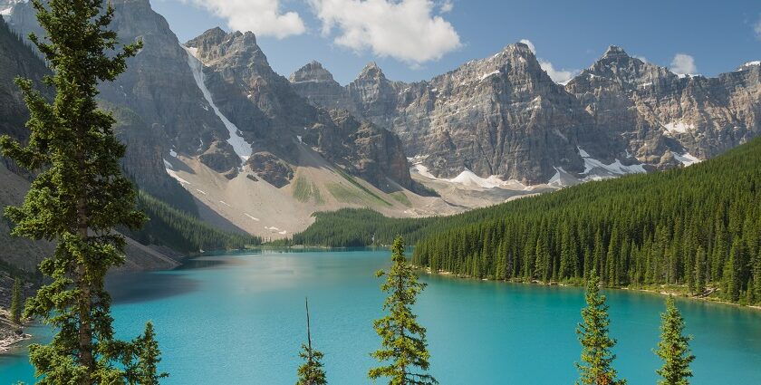 A view of Moraine Lake in Banff National Park, surrounded by snow-capped mountains and trees.