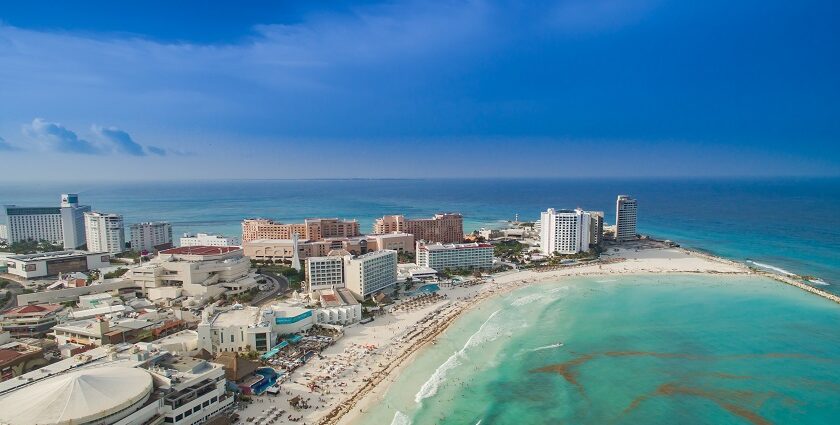 An aerial view of a beach in Cancun, showcasing a curved shoreline and soft, white sand