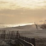 A serene beach near New York, featuring a person strolling along the shore at sunset.