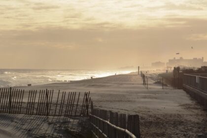 A serene beach near New York, featuring a person strolling along the shore at sunset.