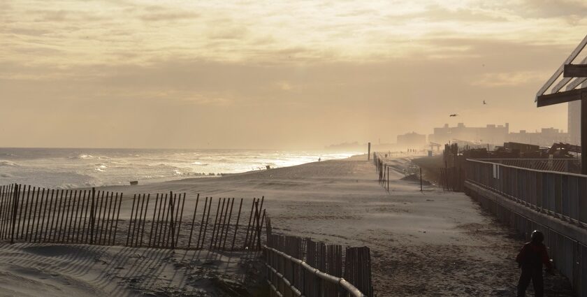 A serene beach near New York, featuring a person strolling along the shore at sunset.