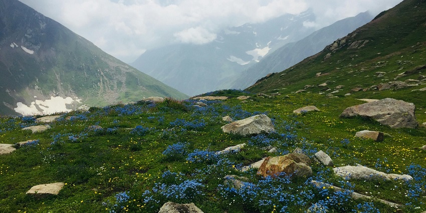 A scenic view of a vast valley surrounded by towering mountains under a partly cloudy sky