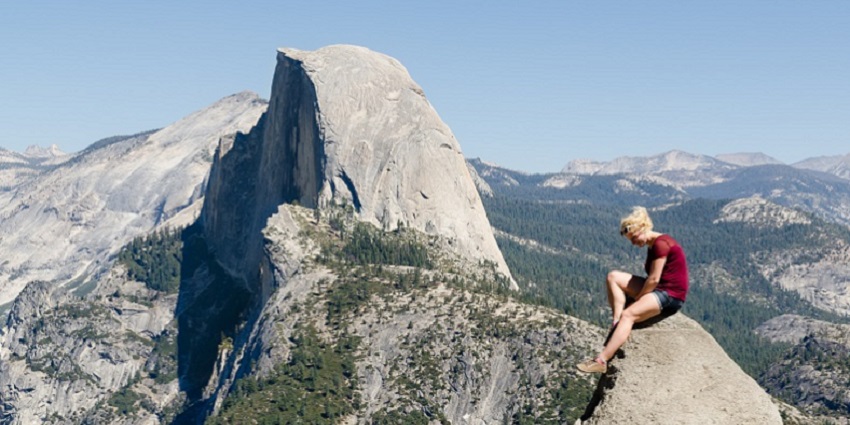 Girl posing with a scenic mountain backdrop at Glacier Point in Yosemite National Park.