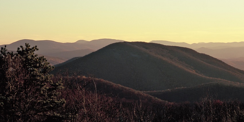 A Wonderful view of Shenandoah National Park with green trees, rolling hills, and mountains under a blue sky.