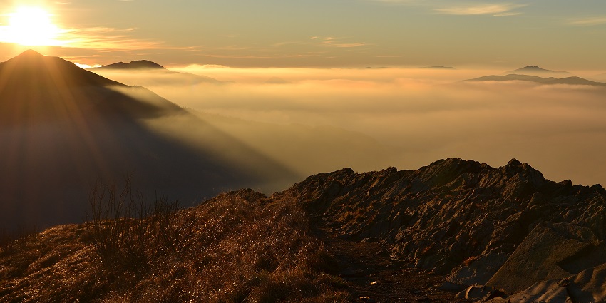 Bieszczady mountains over the clouds with a sunrise and a morning blue sky painted yellow