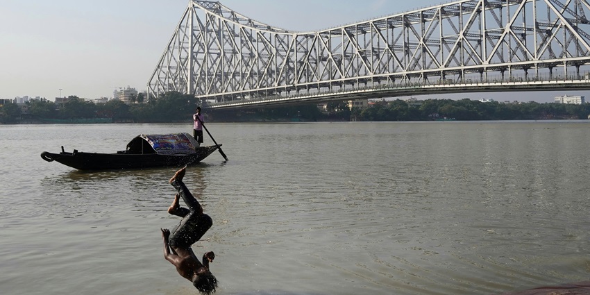Man Jumping into the Hooghly River with the Howrah Bridge in the Background