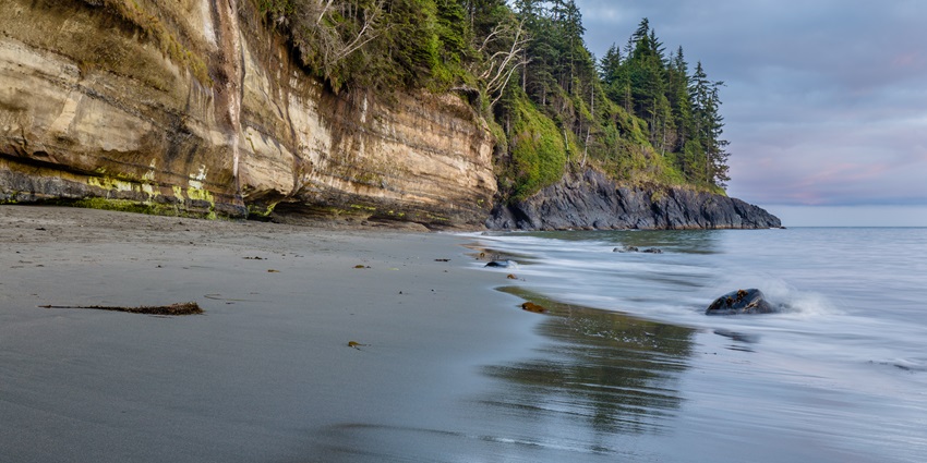 Image of a beach after sunset, with waves lapping the shore under a dusky sky