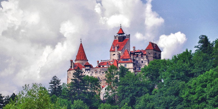 Bran castle with mediaeval architecture, red roofs, grey walls surrounded by greenery