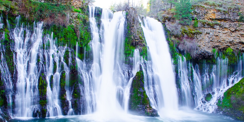 Burney Falls in California, captured in April, with water flowing from a rich, rocky cliff.