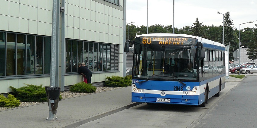 Front entrance of Bydgoszcz Ignacy Jan Paderewski Airport with people entering and a car