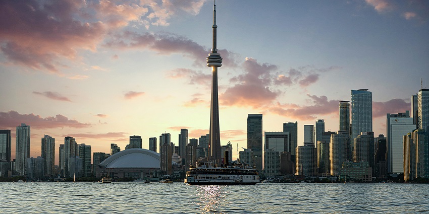 A view of the CN Tower amidst two other tall towers and blue skies above
