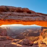 Sunrise through Mesa Arch at Canyonlands National Park, showcasing vibrant orange skies.