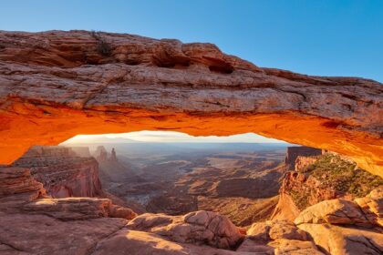 Sunrise through Mesa Arch at Canyonlands National Park, showcasing vibrant orange skies.