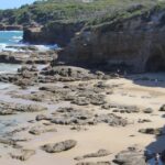 Waves crashing against rock formations at scenic Caves Beach