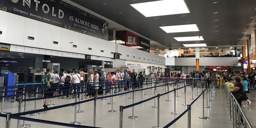 Interior of Cluj-Napoca International Airport with arrival terminal signage and people