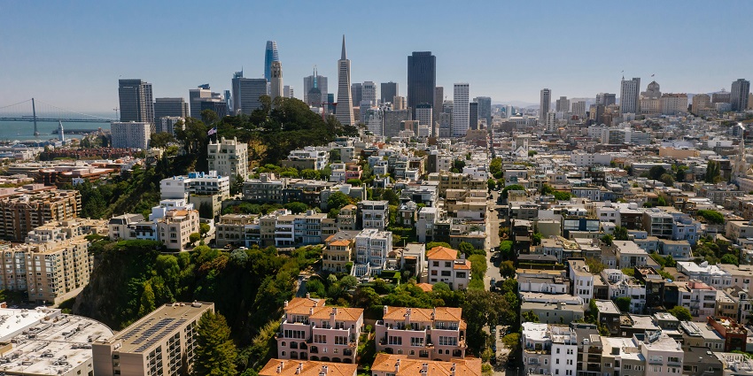 An aerial view of the Coit Tower, which is surrounded by greenery amidst a city.