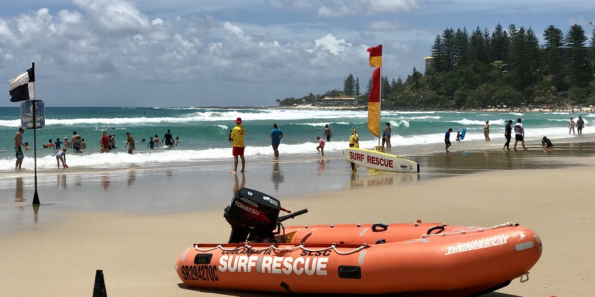 Tourist enjoying the waves under the watchful eyes of a lifeguard at Coolangatta beach