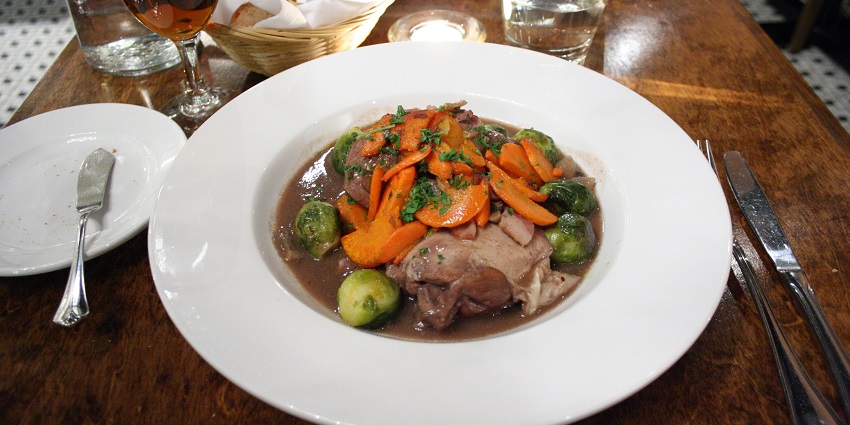 An image of a traditional French coq au vin made with chicken and wine.