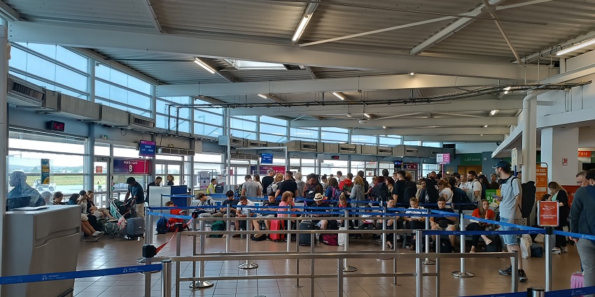 Inside the Craiova International Airport, people sitting and handling their luggage.
