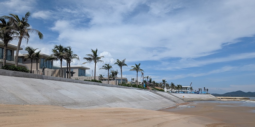 A picture of a beach with golden sands, surrounded by palm trees around a resort