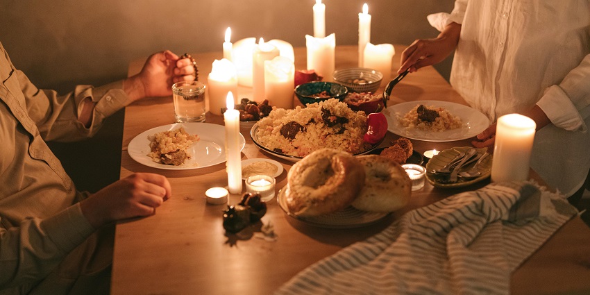 Dinner table with a couple of candles, a champagne bottle, flowers and clear glass