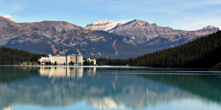 Lake Louise mirrors an image of a nearby hotel with a mountain in the background.