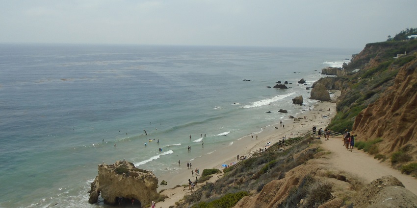 An image of El Matador State Beach, featuring rugged rock formations, golden sand, and gentle waves.
