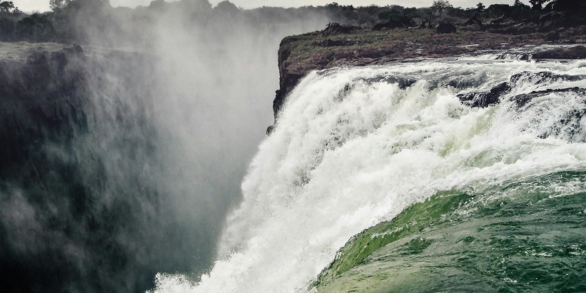 Stunning multi-tiered waterfall amid lush alpine meadows and rugged cliffs.
