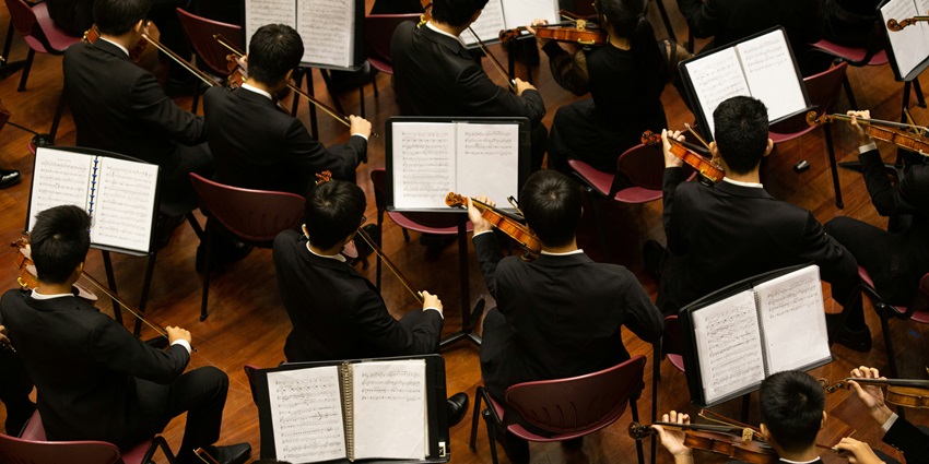 An inside view of the famous Symphony Orchestra featuring musicians playing violins.