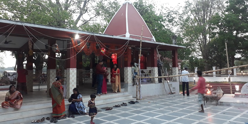 A picture of a temple complex with visitors worshipping the deity