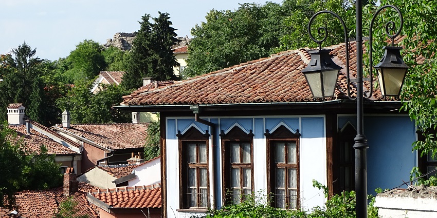 Plovdiv’s old town with traditional-style houses, street lamps, and green trees