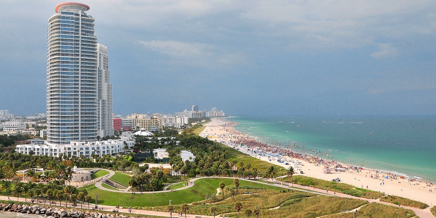 South beach of Miami with a distant crowd of people on the beach and a tall building.