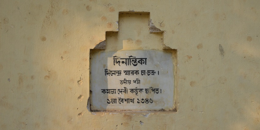 A picture of a wall at an ashram with a Bengali text inscribed over it