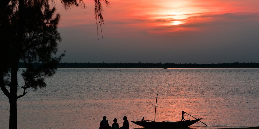 A breathtaking view of sun setting down behind glistening waters in Falta, West Bengal.