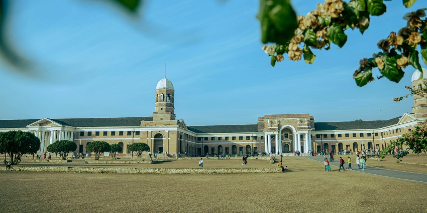 Image of a a large building with a clock tower in the middle of it during day time