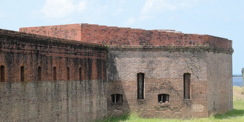 An image of a red wall around green grasses showing the Fort Clinch State Park, Florida.